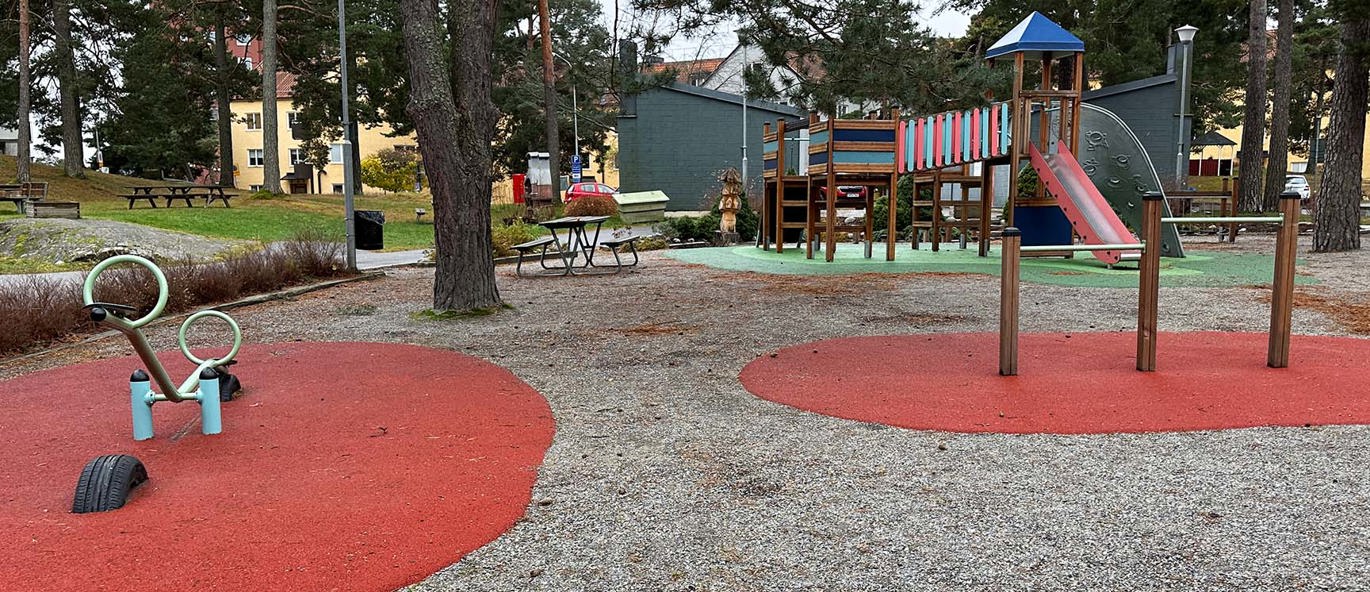 Lekeplass med klatrestativ, voltstang og vippehuske i et boligområde.