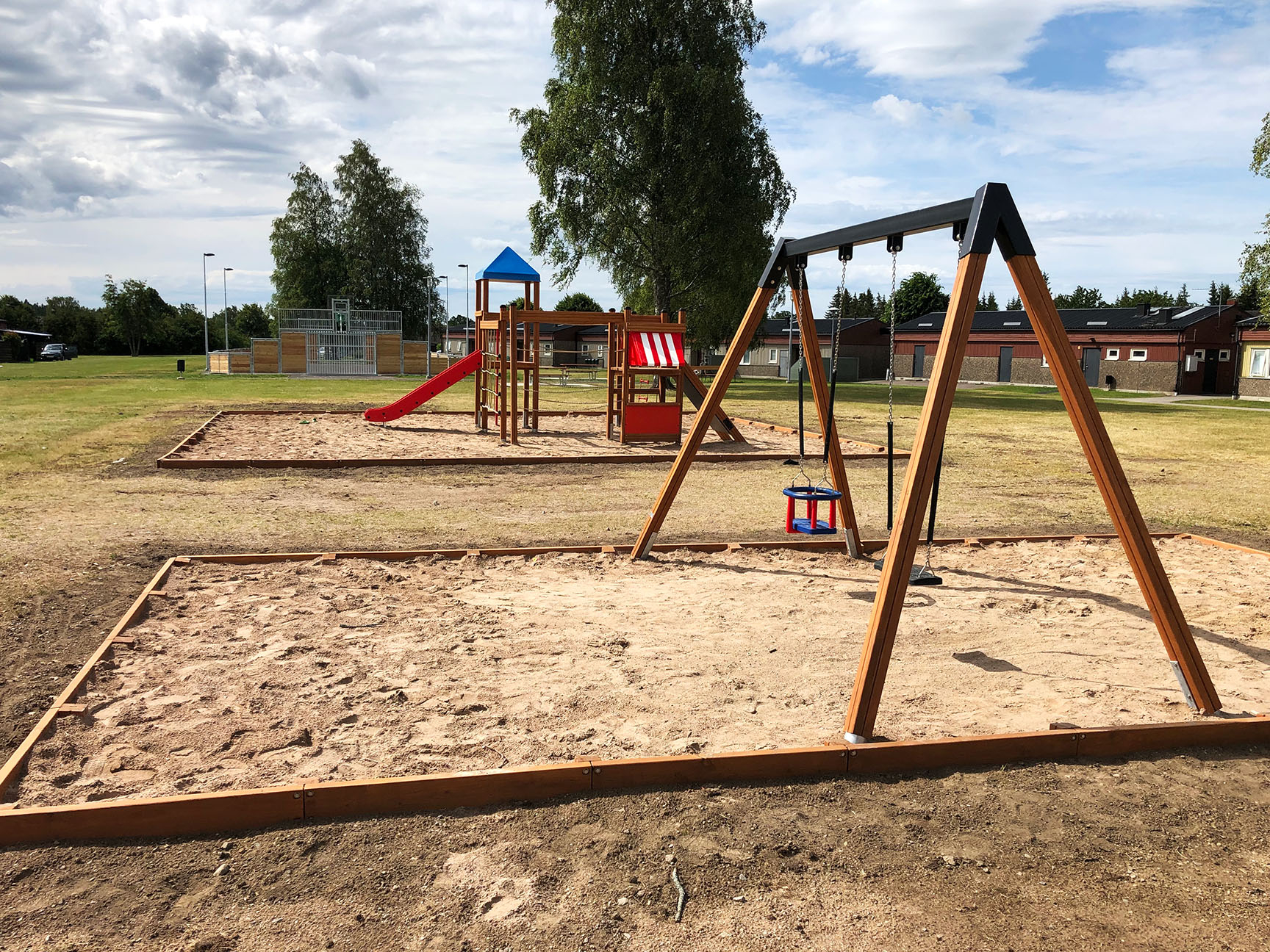 Huskestativ og klatrestativ med grusunderlag i et boligområde.